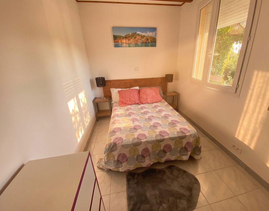 Chambre double avec tête de lit en bois et vue sur le jardin – Gîte Villa Jeff
