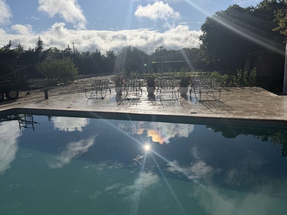 Piscine avec reflets du ciel et plage travertin